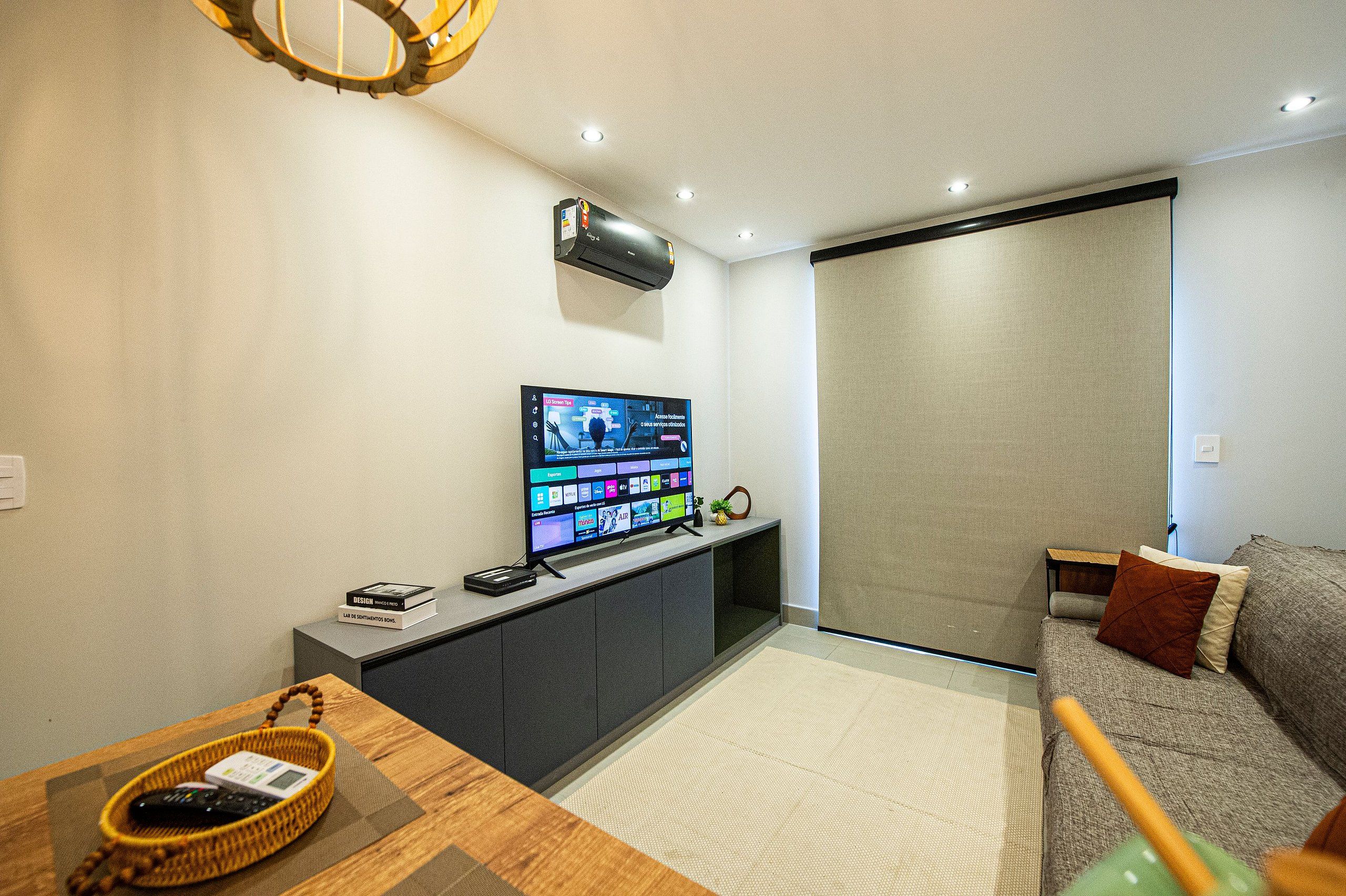 A modern living room with a flat-screen TV, a sofa, a coffee table, and a small side table.