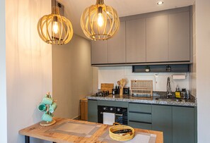 Una cocina moderna con armarios oscuros, encimera de granito y dos lámparas colgantes.