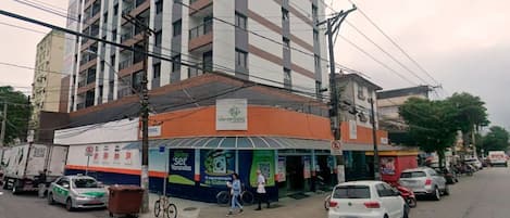 Un edificio de varios pisos con planta baja comercial que incluye una farmacia y un café.