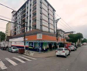 Un edificio de varios pisos con planta baja comercial que incluye una farmacia y un café.
