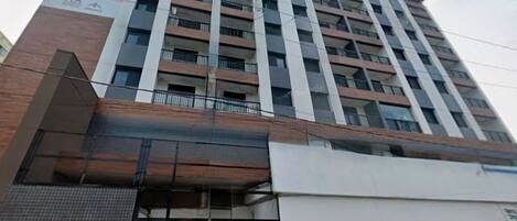 Ein mehrstöckiges Gebäude mit modernem Design, das Glas- und Backsteinfassaden kombiniert, und einen markanten Eingang mit einer Glastür.
