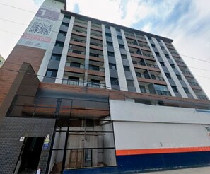 A multi-story building with a modern design, featuring a mix of glass and brick facades, and a prominent entrance with a glass door.