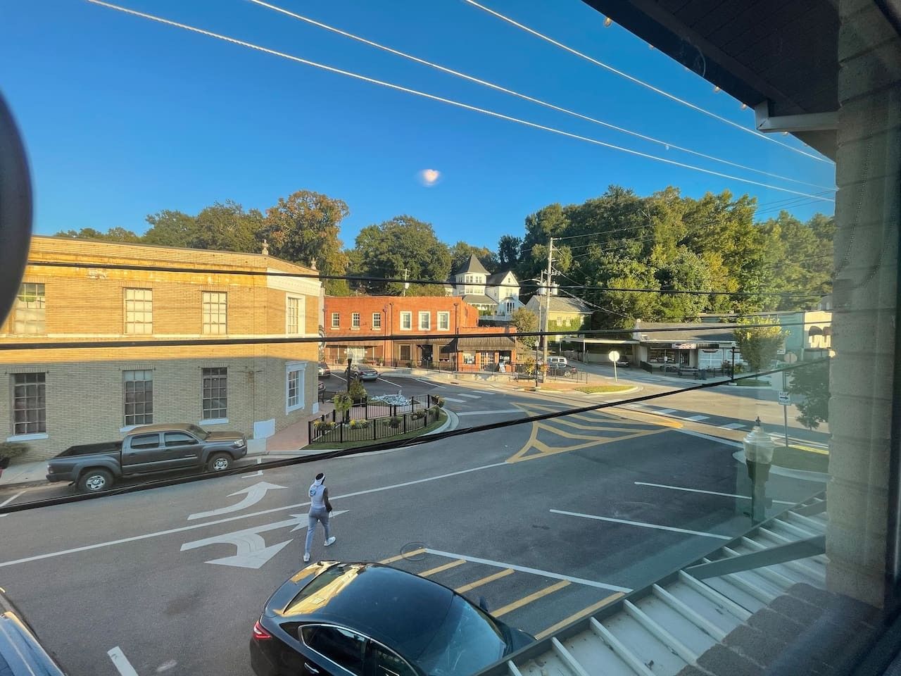 Une vue de rue avec des bâtiments, un ciel dégagé et une voiture garée.