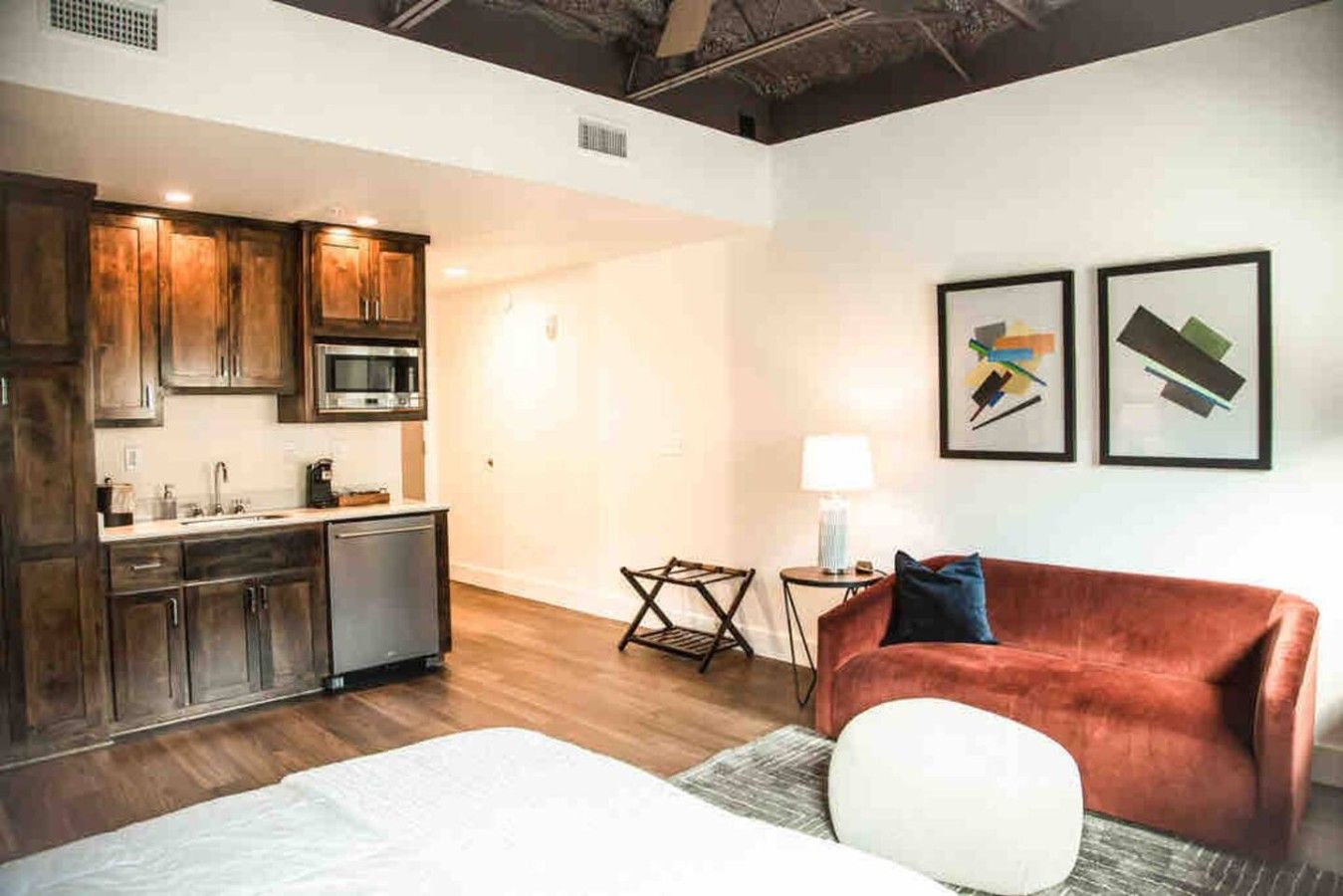 Une chambre moderne équipée d’une kitchenette, d’un canapé et de deux œuvres d’art encadrées accrochées au mur.