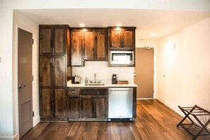 Una cocina compacta con armarios de madera oscura, un microondas integrado y un lavavajillas.