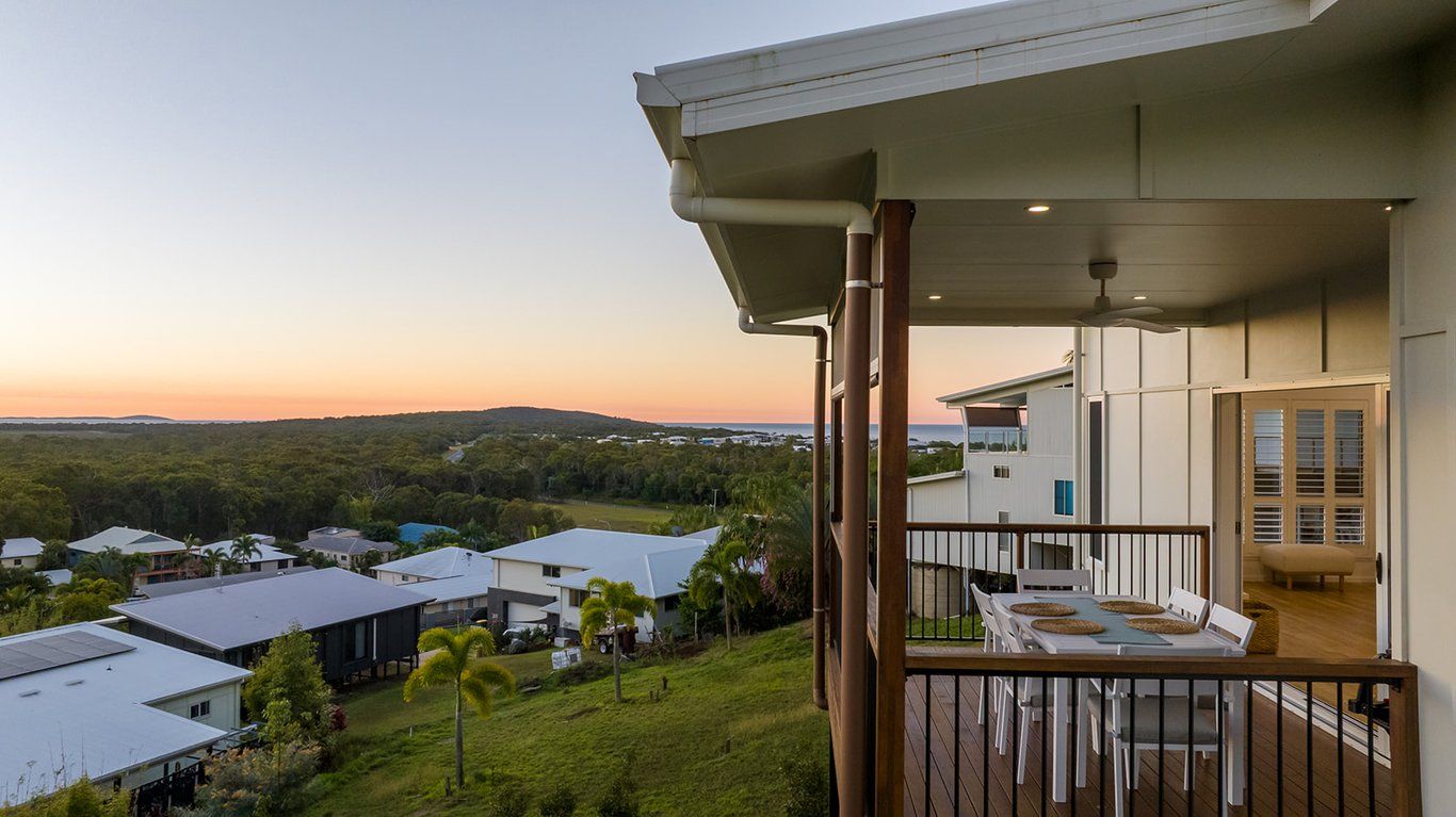 A balcony with a view of a residential area and hills in the distance.