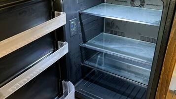 Un refrigerador vacío con varios estantes y un panel de control.