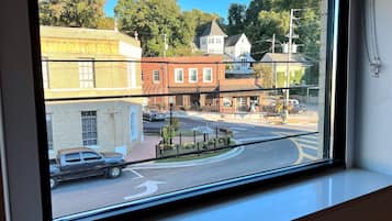 A view through a window of a street with buildings, a roundabout, and a parked truck.