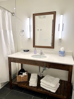 A bathroom with a white sink, a wooden vanity, a mirror, and a towel rack. - The Lofts Suite #21 `The Judge` King Bed & Balcony (Wetumpka)