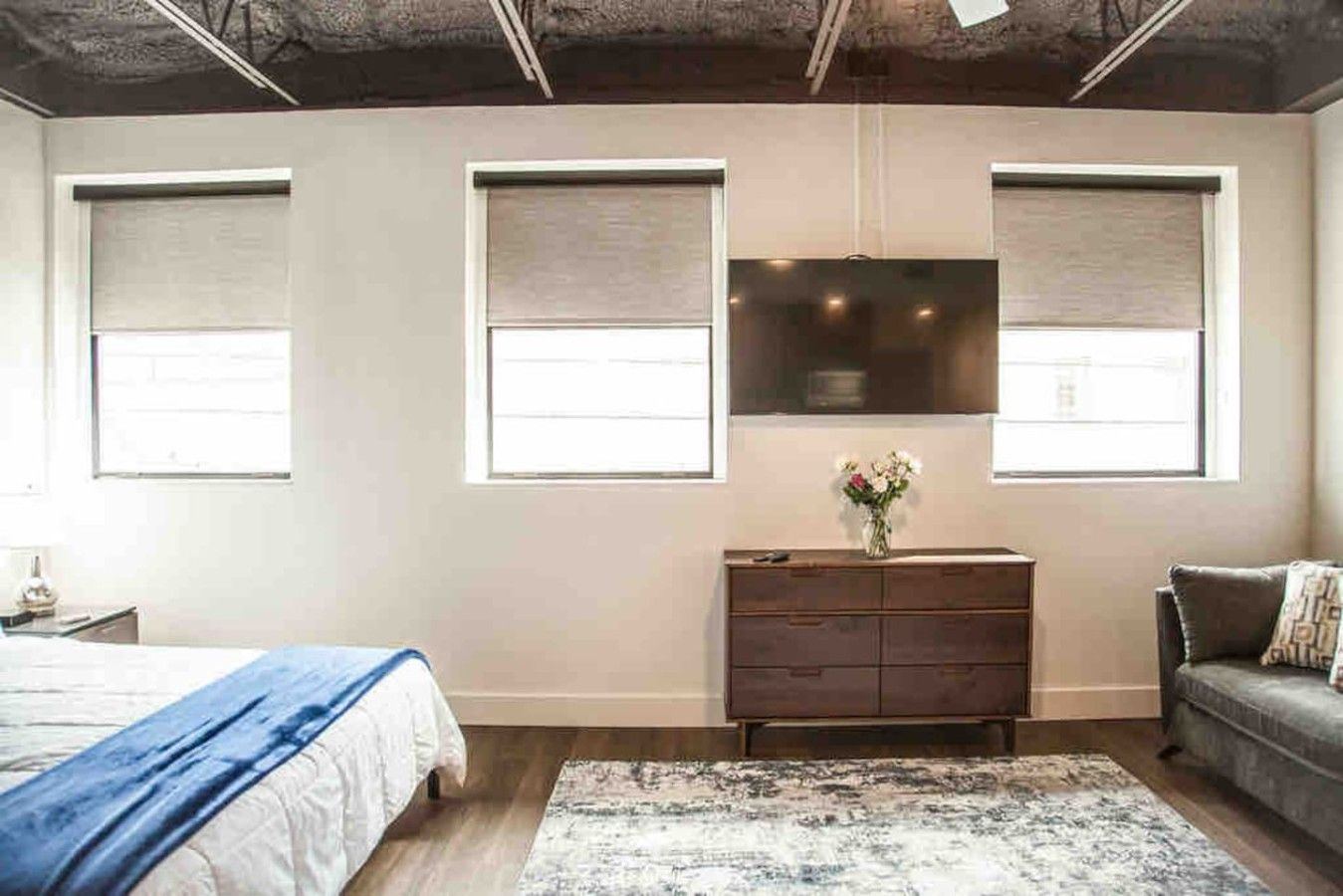 Un dormitorio con cama, cómoda y televisor montado en la pared.