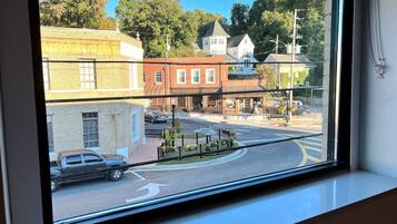 A view through a window of a street with buildings, a roundabout, and a parked truck.