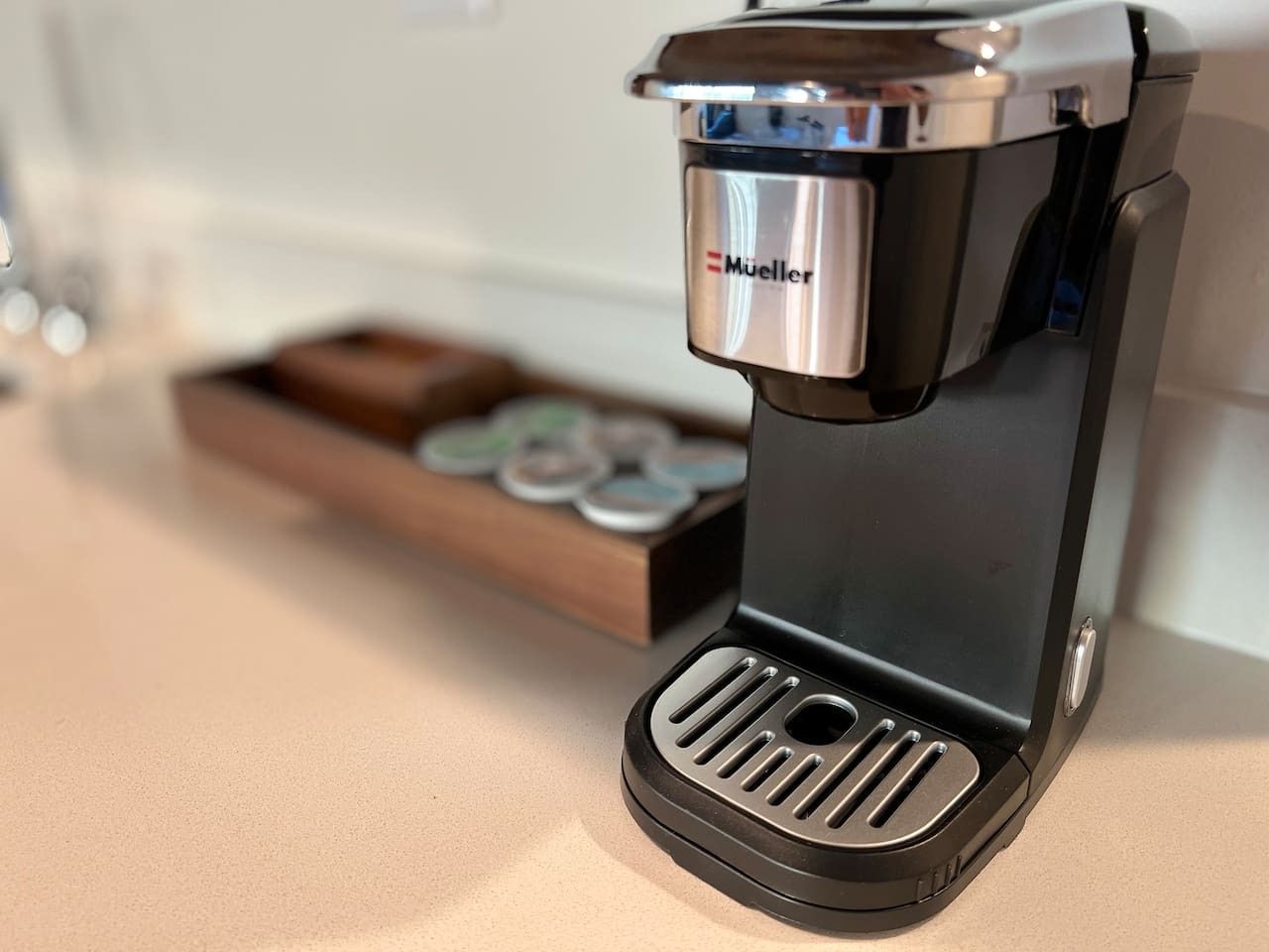 A compact coffee machine with a metallic top and a black base, placed on a countertop.