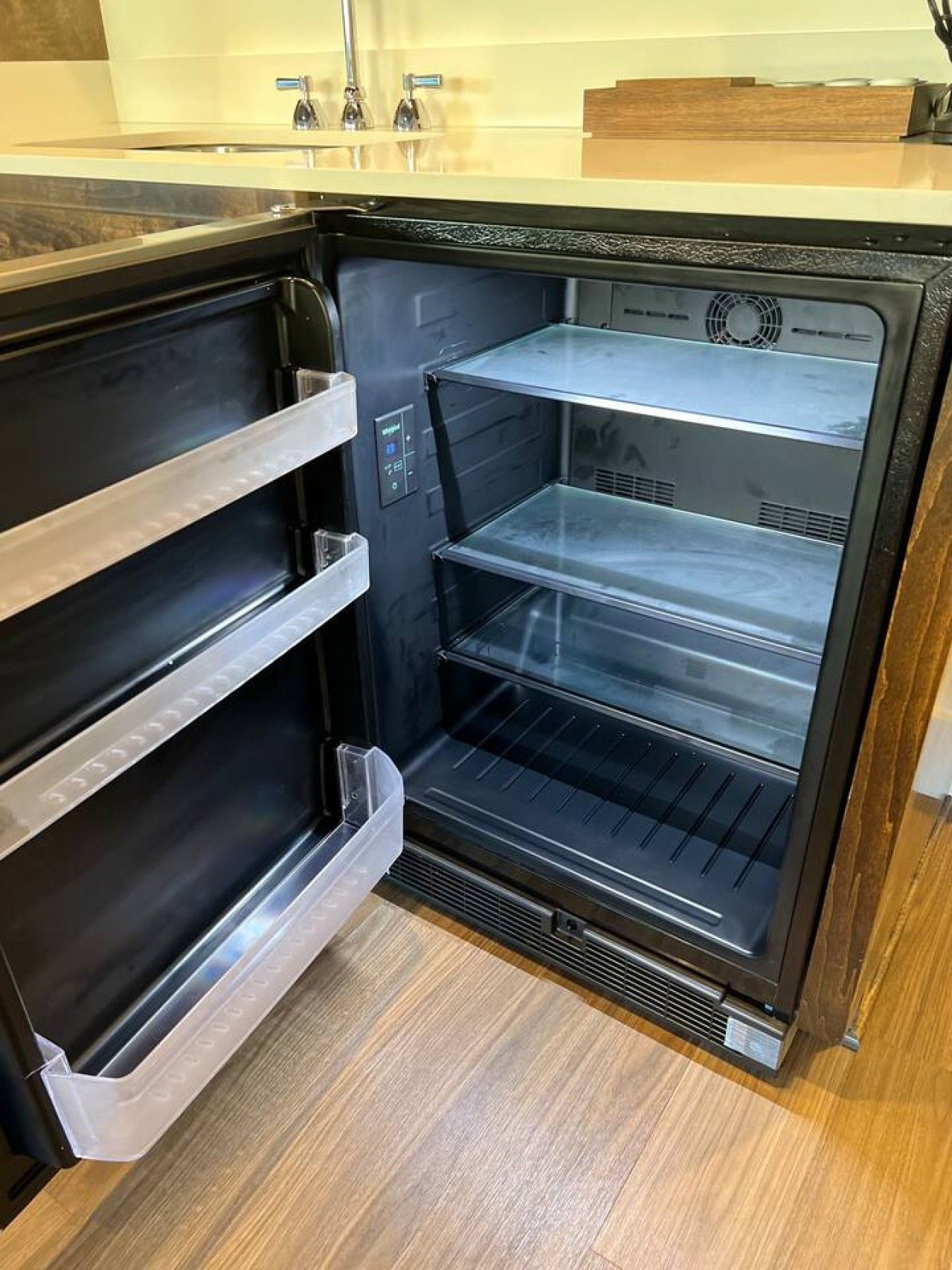 Un refrigerador vacío con varios estantes y un panel de control.