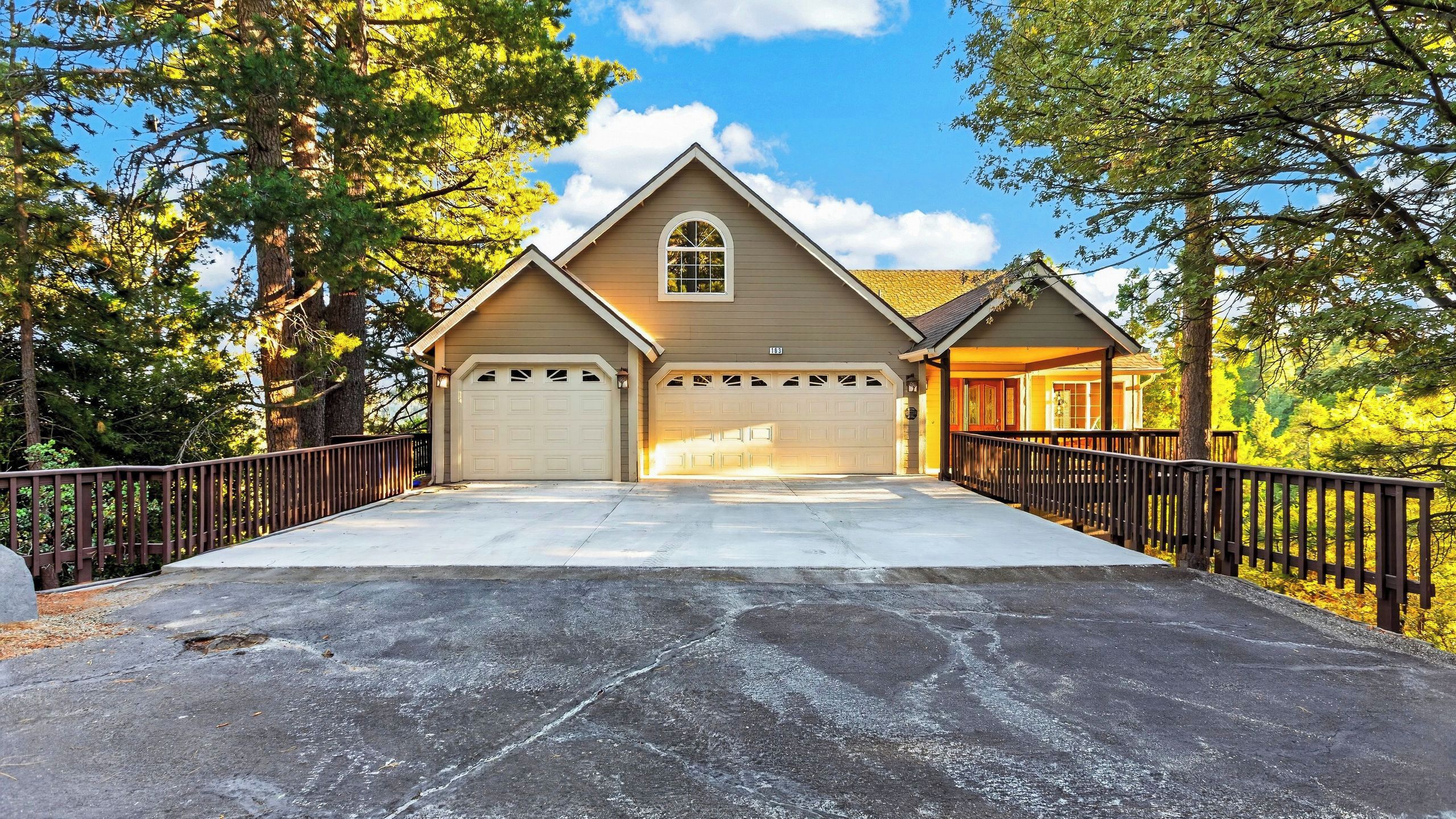 Ein zweistöckiges Haus mit Garage, überdachter Veranda und Auffahrt.