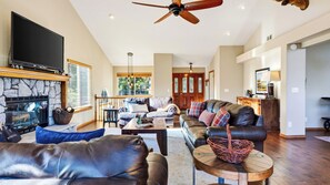 A spacious living room with a fireplace, leather sofas, a television, and a dining area. - Poolside Pines Reunion House by Avantstay Private Pool + Hot Tub + Gym Mins to the Lake (Twin Peaks)