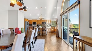 A spacious kitchen with wooden cabinets, a dining area with a large table, and a view through a sliding glass door. - Poolside Pines Reunion House by Avantstay Private Pool + Hot Tub + Gym Mins to the Lake (Twin Peaks)