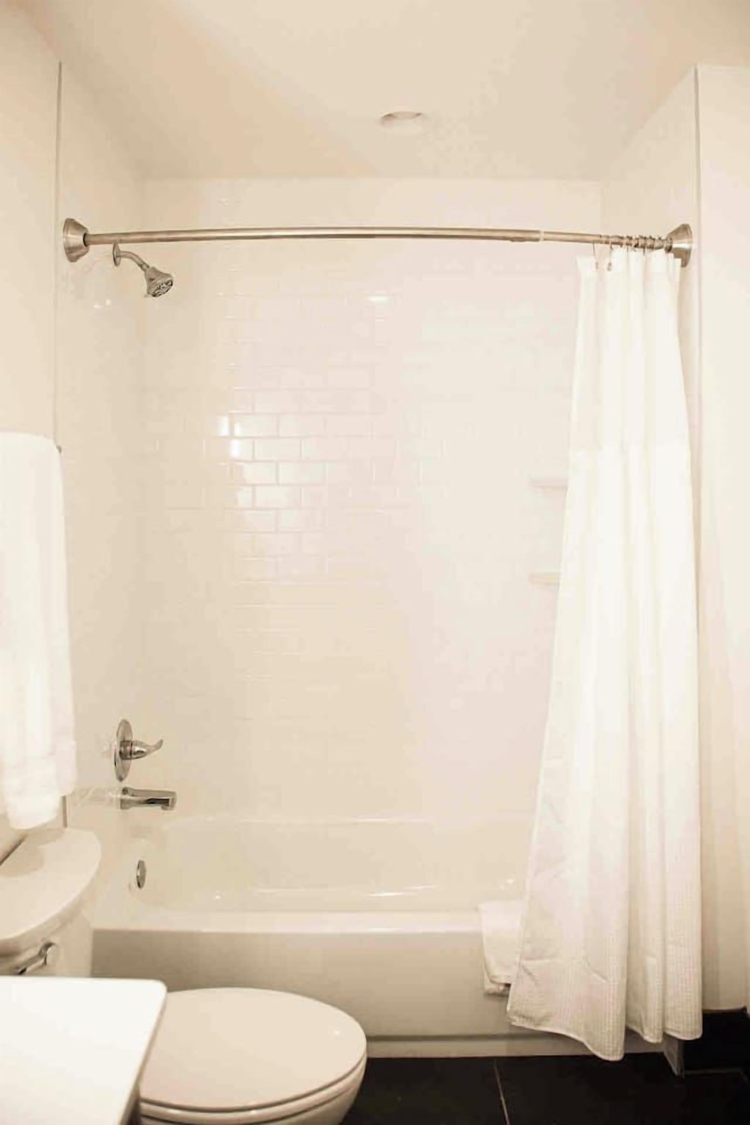 A bathroom with a bathtub, toilet, and a shower curtain.