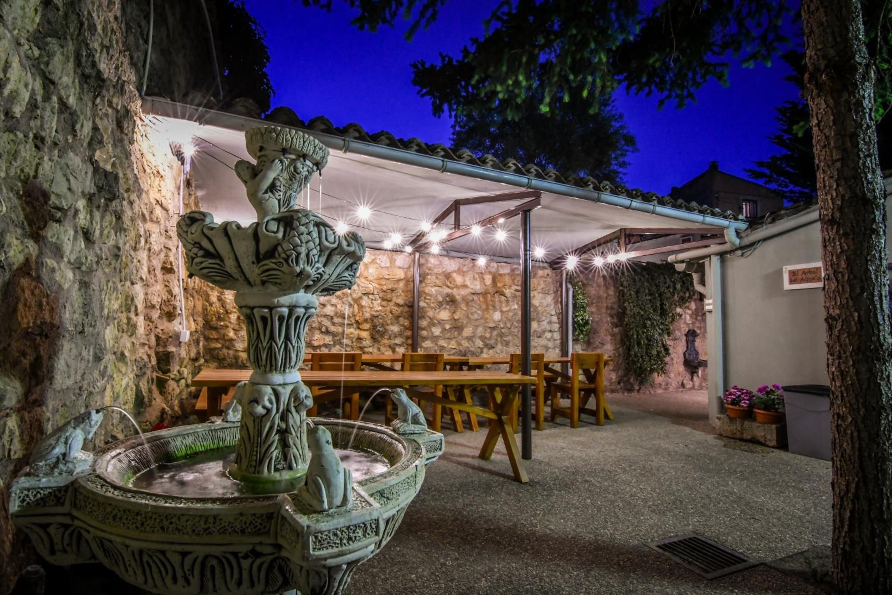 An outdoor patio area with stone walls, a fountain, and a covered seating area.