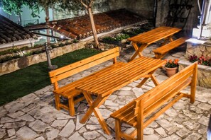 Eine Außenpatio mit Steinböden, Holzbänken und einem kleinen Gartenbereich mit Topfpflanzen.