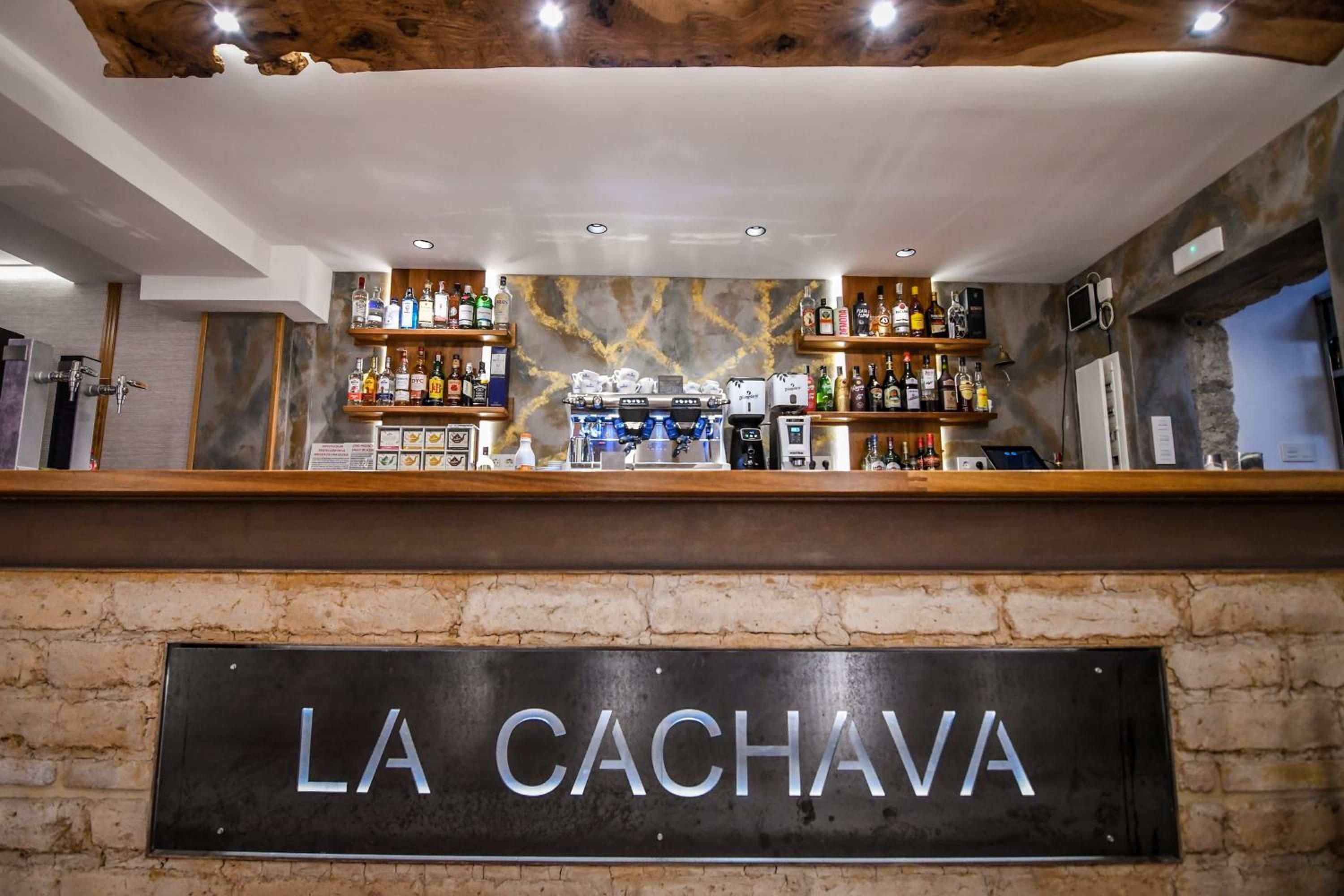Una zona de bar con un letrero que dice 'LA CACHAVA' y estantes llenos de diferentes botellas.