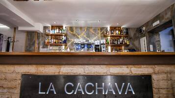 Una zona de bar con un letrero que dice 'LA CACHAVA' y estantes llenos de diferentes botellas.