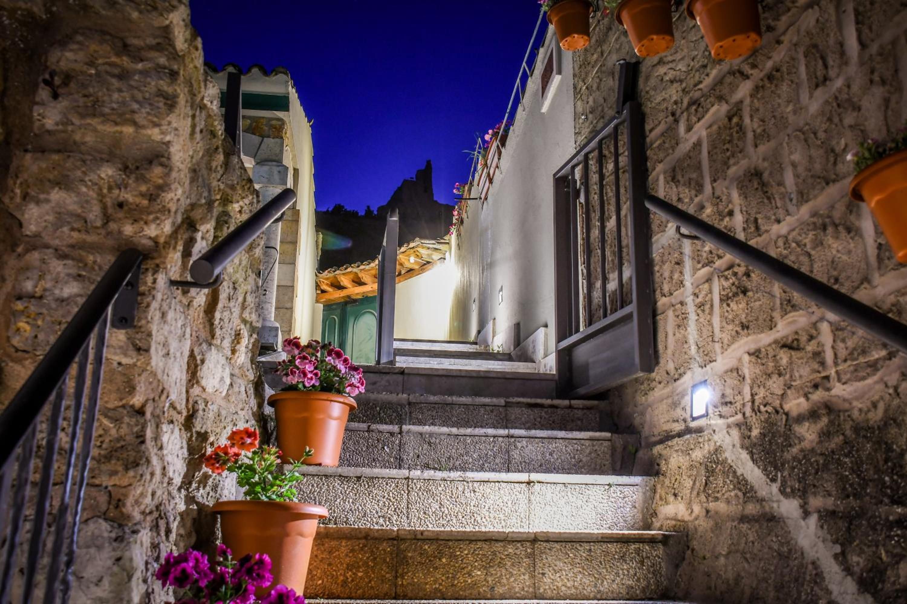 A narrow stone staircase leading to a building entrance with terracotta pots on the steps.