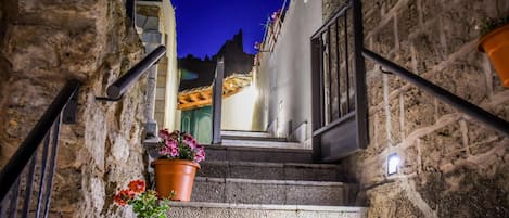 A narrow stone staircase leading to a building entrance with terracotta pots on the steps.