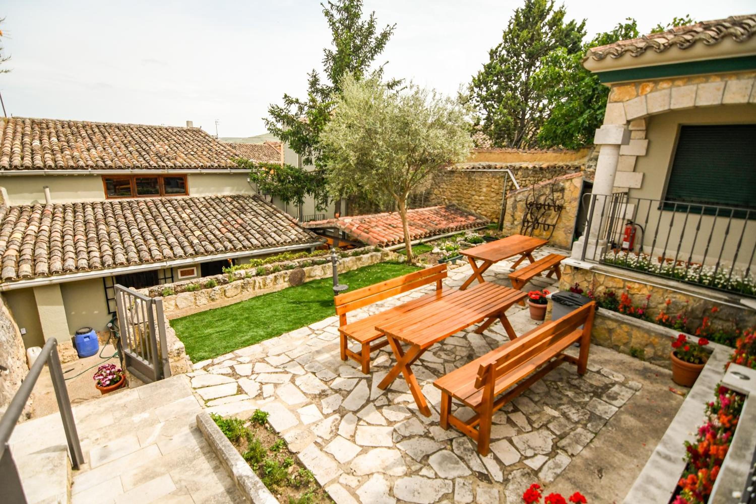 Eine Terrasse mit Steinboden, Holzmöbeln und einem kleinen Gartenbereich.