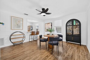 Een moderne eetruimte met een ronde tafel, stoelen en een plafondventilator.