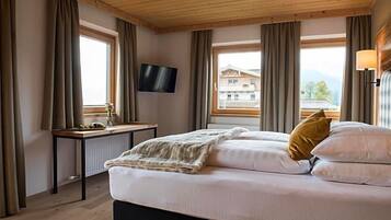 Ein Schlafzimmer mit einem Bett, einem Schreibtisch, einem Fernseher und einem Fenster mit Vorhängen.