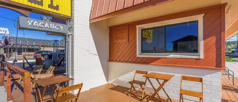 An outdoor seating area with wooden tables and chairs, a visible 'VACANCY' sign, and a building with a window displaying '401'.