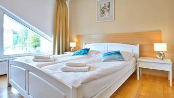 A hotel room with a large bed, two bedside tables, a window with curtains, and a framed picture on the wall.