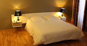 A neatly made bed with white bedding in a room with wooden flooring. - Au Pavillon Du Frene (Lacaune)