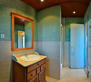 Un baño con lavamanos, espejo y armario.