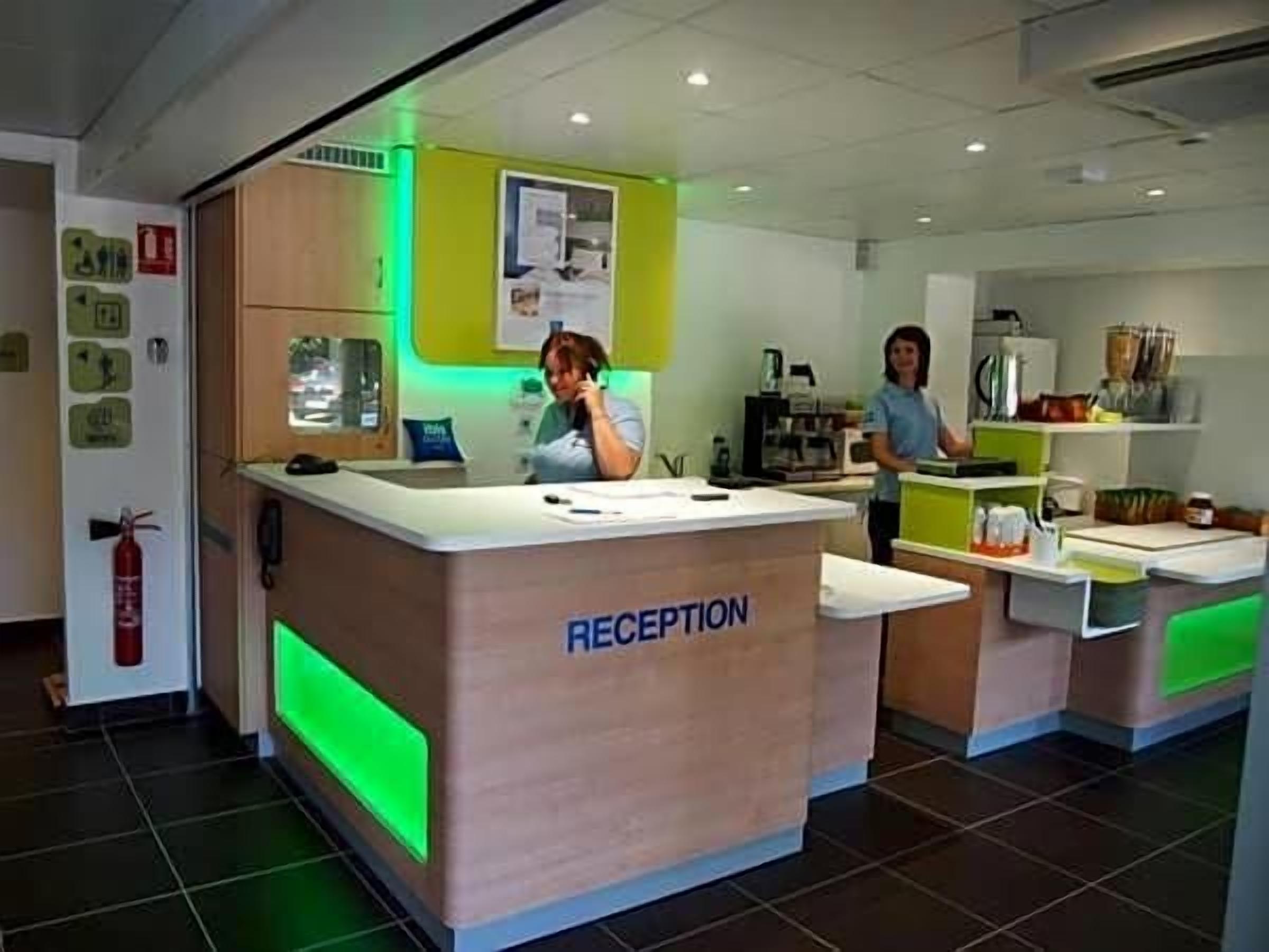 Un espace d’accueil comprenant un comptoir de réception, un extincteur et un présentoir avec divers articles.