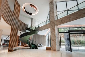 A modern interior with a spiral staircase, high ceilings, and large windows.