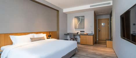 Una habitación de hotel moderna con una cama grande, un escritorio y una kitchenette.