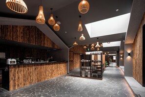 A modern interior with a reception desk, bamboo wall panels, and a variety of hanging pendant lights.