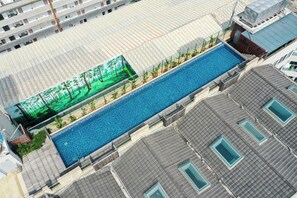 A swimming pool with a surrounding deck, adjacent to a building with multiple windows and a tiled roof. - The Luzerne Hotel (Quanzhou)
