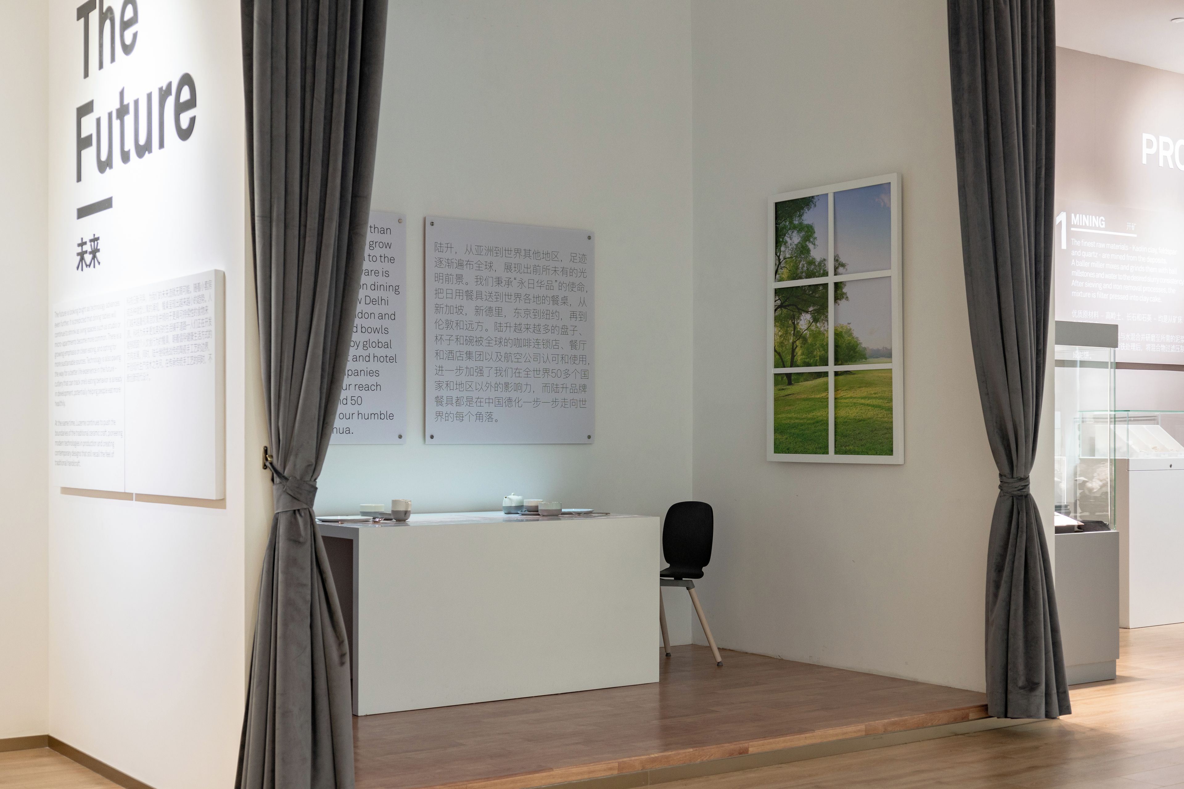 A modern interior with a reception desk, informational posters, and a window with a view of greenery.