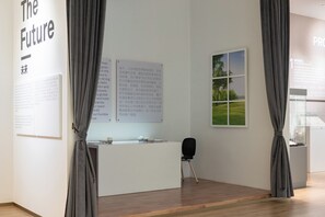 Un intérieur moderne avec un comptoir d’accueil, des affiches d’information et une fenêtre donnant sur un espace verdoyant.