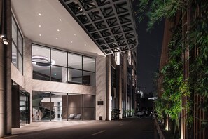 Un edificio moderno con fachada de vidrio, un acceso cubierto y una escalera que conduce a un nivel superior.