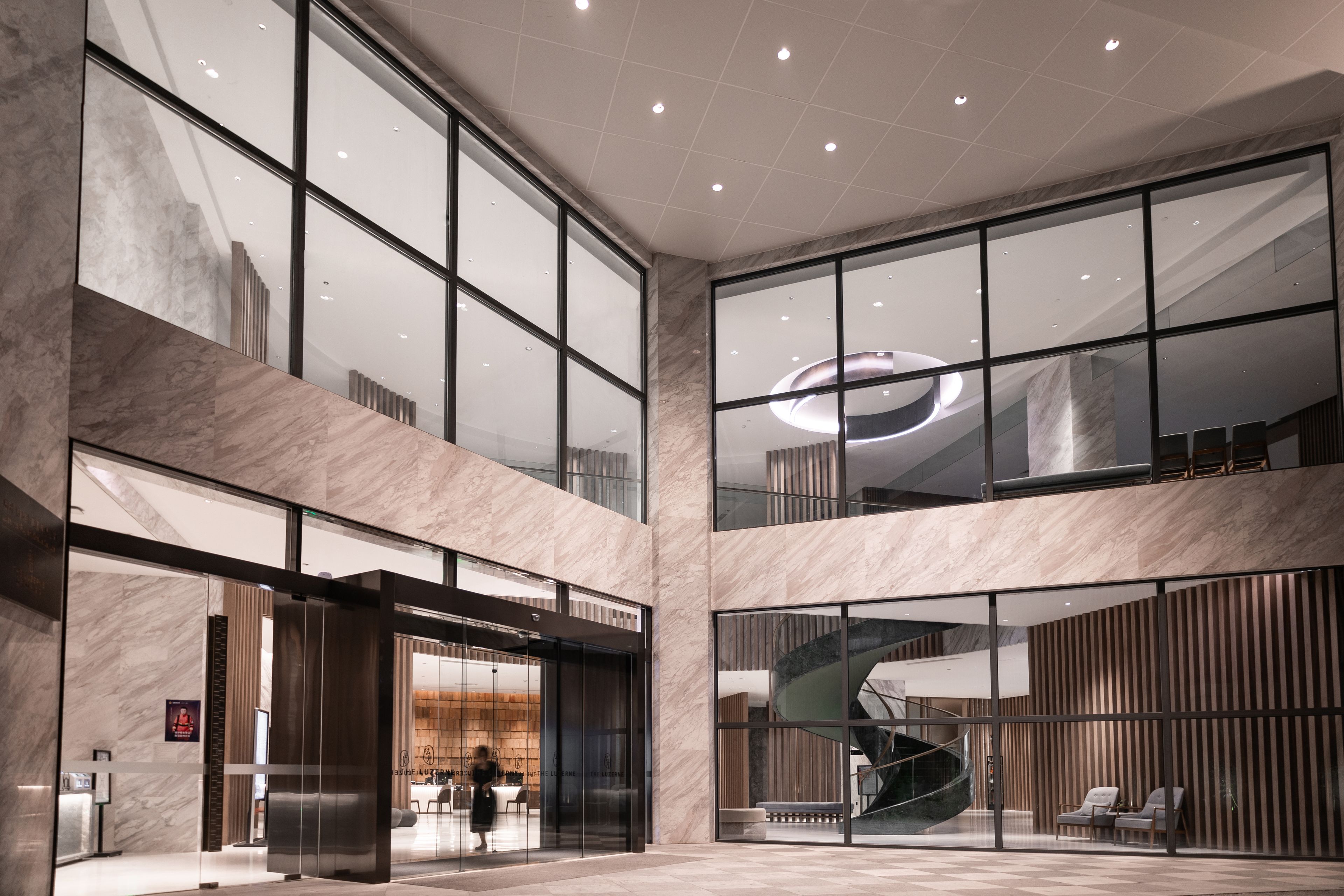 A spacious lobby with a grand staircase, marble walls, and a modern reception area.