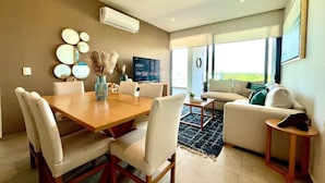 Uma sala de estar moderna com área de jantar, sofá e televisão de tela plana.