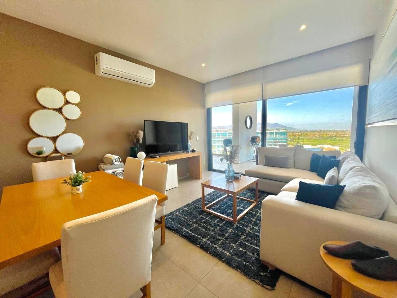 A modern living room with a dining area, a flat-screen TV, and a sofa with a view.