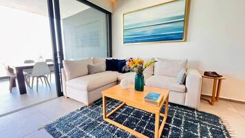 A modern living room with a sofa, coffee table, and a painting on the wall.