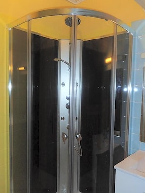 Box de chuveiro envidraçado com porta curva, chuveiro e painel de controle.
