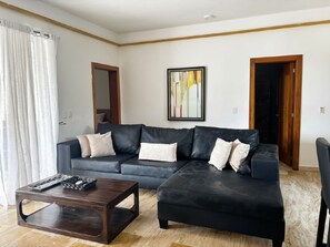 A living room with a sectional sofa, a coffee table, and a framed artwork on the wall. - Casa Verde:  Your Tropical Escape in SOV (Sosua)