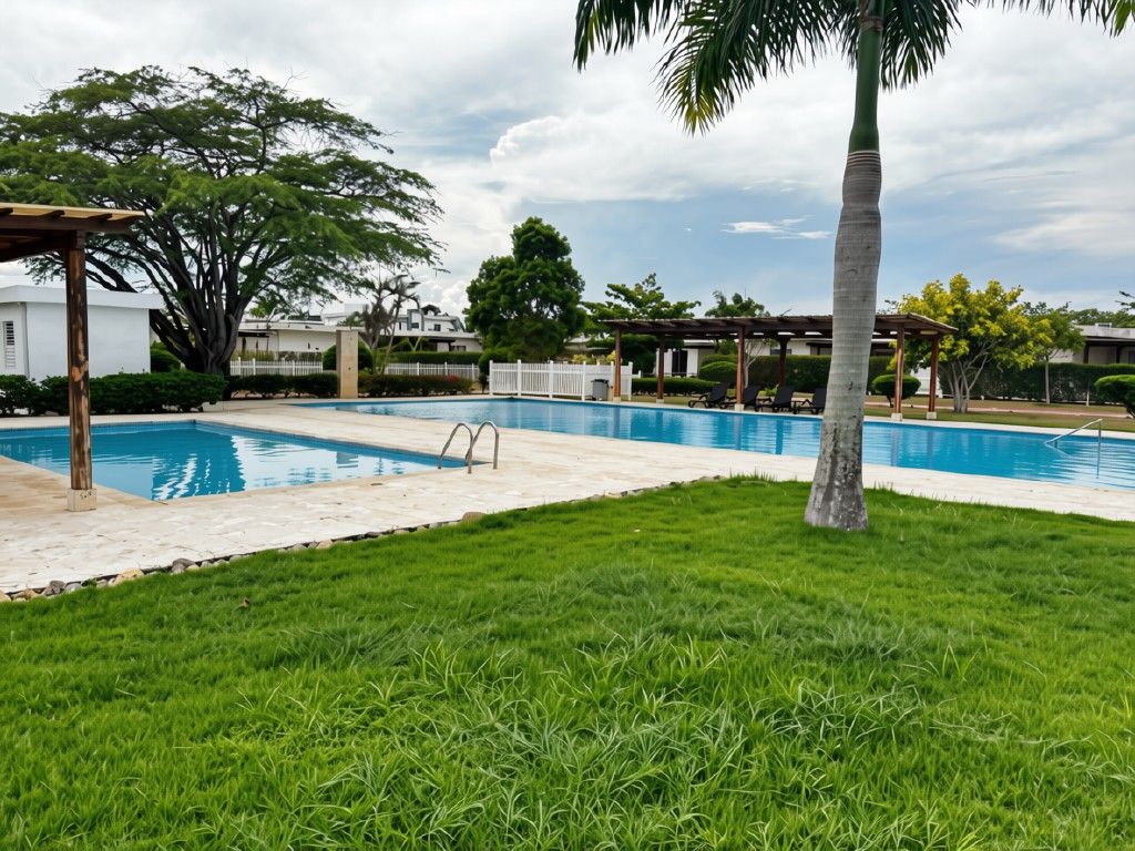 A swimming pool with a wooden deck, surrounded by grass and trees.
