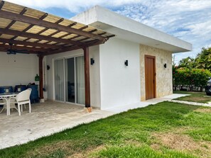 A modern house with a covered patio, a sliding glass door, and a stone exterior. - Casa Verde:  Your Tropical Escape in SOV (Sosua)